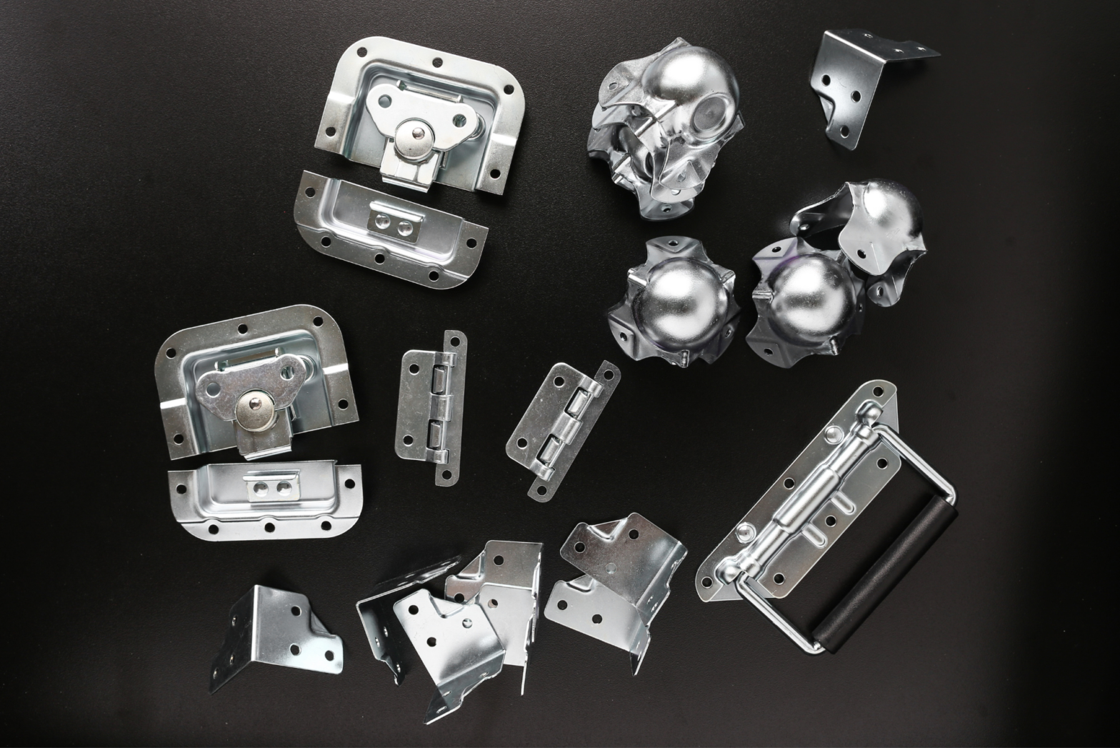 Various high-quality hardware pieces for road cases lie scattered on a black tabletop.