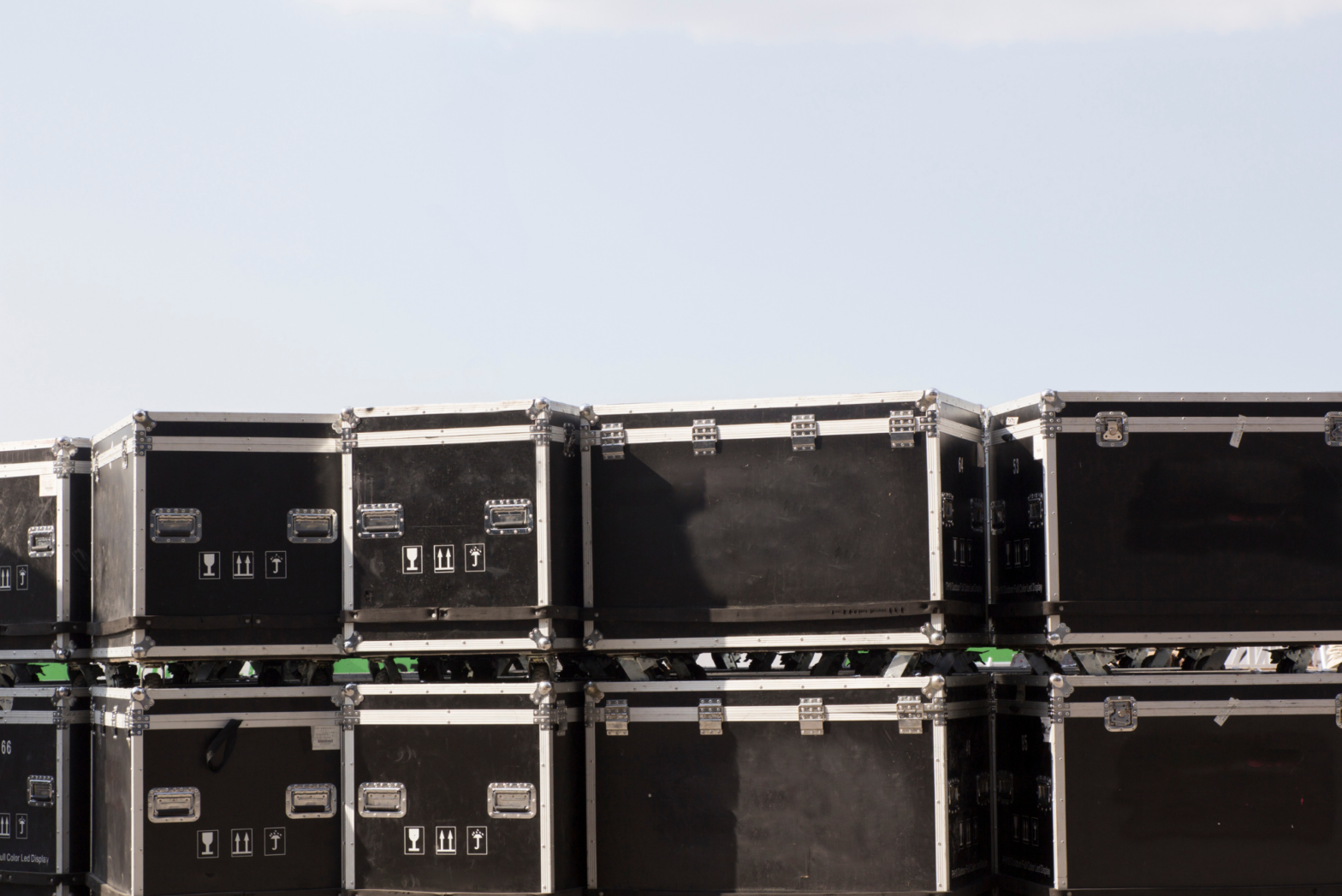 A bunch of black cable trunks with wheels stack one on top of another.