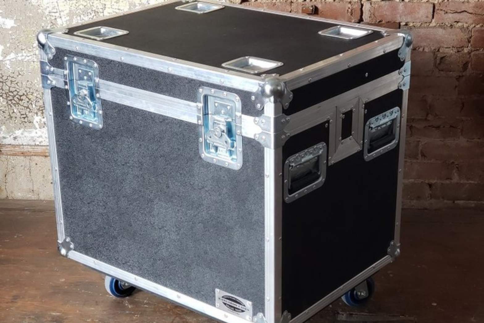 A well-built, high-quality road case made by Kangaroo Cases sits on casters in front of an exposed brick wall.