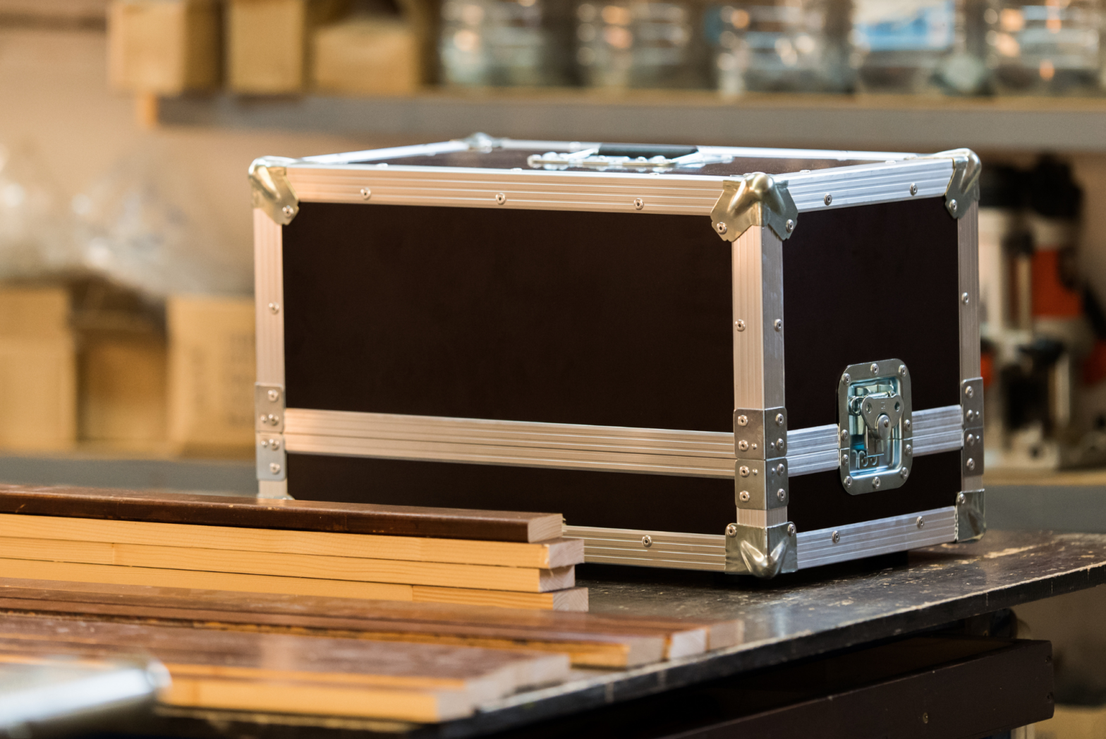 An old road case awaiting repairs sits upside down on a worktable next to a stack of new panels.