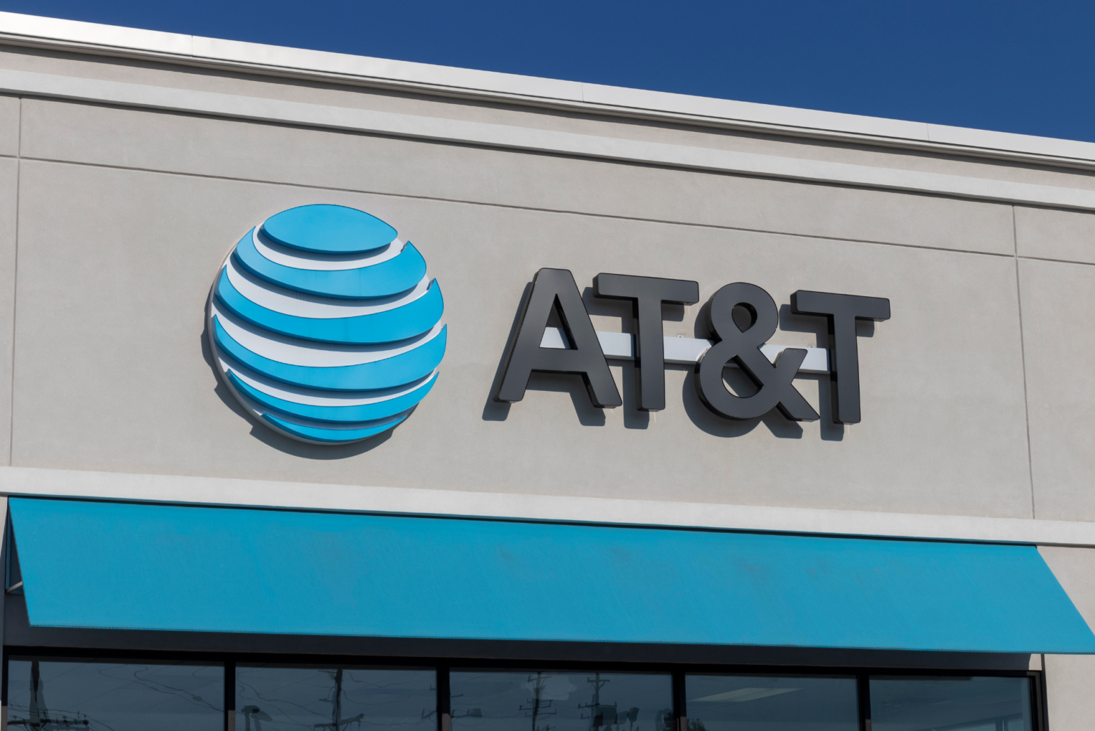 The AT&T logo marquis sits above a blue awning on one of the company’s many storefronts.